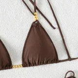 Conjunto de bikini marrón chocolate con corpiño triangular con tirantes finos y detalle de cuentas doradas, y bombacha con tiras laterales ajustables.