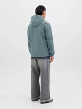 Campera softshell color celeste con capucha ajustable con cordón, mangas largas con puños de canalé, cierre frontal con cremallera y bolsillos delanteros.