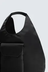 Bolso shopper negro de hombro fabricado en tejido técnico. Tiene un compartimento principal sin cierre, un bolsillo plano y otro con cierre mediante cremallera en el interior. En la parte frontal tiene dos bolsillos con cierre mediante imán y asa de mano.