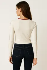 Remera de manga larga color verde militar, ajustada al cuerpo, con cuello redondo ribeteado en blanco y estampado frontal con el número 05 en blanco con borde negro.