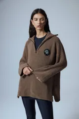 Sweater marrón de punto con cuello polo, cierre de cremallera parcial y parche bordado en el pecho.