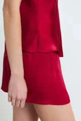 Conjunto de pijama de satén color rojo, compuesto por un top con breteles finos y escote en V adornado con puntilla, y un short con cintura elastizada y lazo regulable.