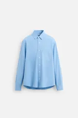 Camisa celeste de lyocell y algodón, corte relaxed fit, cuello solapa, manga larga con puños abotonados, bolsillo de parche en el pecho y cierre frontal con botones.