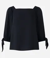 Blusa de mangas 3/4 con elásticos y lazos en los puños, confeccionada en viscosa, con escote cuadrado.