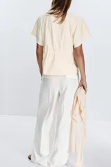 Camiseta color crudo de algodón con cuello redondo, manga corta caída y cintura ajustable con cordón.