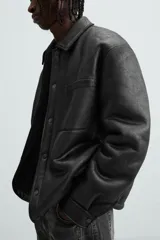 Sobrecamisa marrón de efecto piel con interior de borreguillo a tono, de corte relaxed fit, cuello solapa, manga larga con puños abotonados, bolsillos de plastrón en pecho y laterales, efecto lavado y cierre frontal con botones a presión.