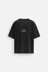 Camiseta negra con efecto lavado, corte relaxed fit, cuello redondo y manga corta. Estampación frontal con texto y parche en la espalda.