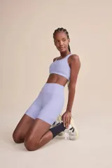 Short deportivo de tiro alto color lila, con tecnología de compresión, protección solar UV 50+, forro estratégico para evitar transparencias, dos bolsillos laterales sin costuras visibles y barra con gripper para un ajuste seguro.