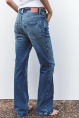 Pantalón de jean azul de tiro alto, corte bootcut, con cinco bolsillos, cierre frontal con cremallera y botón.