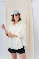 Camisa color crema de algodón liviano, calce oversize, con cuello camisero, cierre abotonado, mangas largas con opción de arremangado y dos bolsillos frontales con solapa.