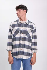Sobrecamisa de franela a cuadros azul marino, gris y blanco, con cuello clásico, cierre frontal con botones, dos bolsillos de parche en el pecho y mangas largas con puños abotonados.