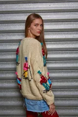 Sweater tejido color crema con diseño de esquiadores en colores.