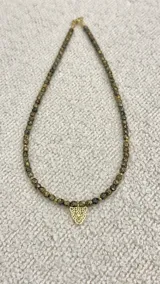 Collar de cuentas color marrón y negro con dije de leopardo dorado.
