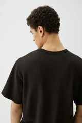Remera negra de algodón pesado con textura waffle, cuello redondo ribeteado acanalado y corte estándar.