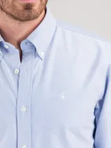 Camisa celeste de hombre, marca El Ganso, de corte regular fit, cuello button-down, manga larga con puño simple y logo bordado en el pecho. Confeccionada en tejido oxford compuesto por 93% algodón y 7% algodón reciclado.