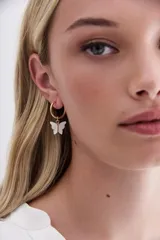 Aros dorados tipo argolla con dije de mariposa nacarada.