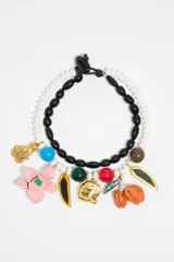 Collar doble con cuentas blancas y negras, con dijes colgantes de animales, flores y hojas en colores variados.