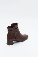 Bota corta de caña baja color negro, con puntera cuadrada, taco medio y tira decorativa con hebilla metálica en el lateral.