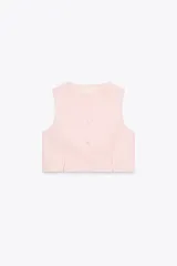 Chaleco color rosa pálido de cuello redondo y sisa. Bajo con aberturas delanteras y cierre frontal con botones.