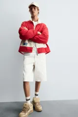 Bermuda de denim color blanco roto con efecto encerado, corte amplio (baggy fit) y cinco bolsillos. Presenta cierre frontal con cremallera y botón.