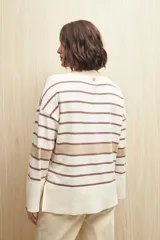 Sweater de rayas horizontales color crudo y marrón, con cuello redondo a contratono color beige, tajos laterales y mangas largas con puño ancho.