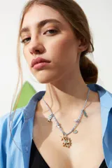 Collar con cordón azul y blanco trenzado, con dijes metálicos dorados y celestes con forma de estrella de mar, pez, alga y caracol.