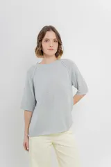 Buzo ligero de tejido fino color gris, con calce relajado, mangas 3/4 y escote redondo.