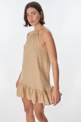 Vestido corto color beige, con escote halter, tirantes finos y falda con volados.