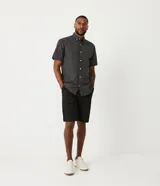 Camisa de hombre de corte clásico, color gris oscuro con estampado de cuadros blancos, cuello abotonado, manga corta y cierre frontal con botones blancos.