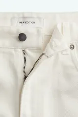 Bermuda blanca de denim rígido de algodón, corte holgado, tiro bajo, cinco bolsillos, raya adelante y atrás, y cierre con botón.