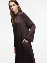 Vestido largo color crema, con cuello mao con lazo ajustable, mangas largas amplias y tajos laterales.