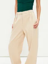 Pantalón gris oscuro de corte amplio, con pinzas en la cintura y bolsillos laterales.
