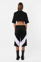 Remera corta negra de calce oversize confeccionada en jersey de algodón. Cuello de ribb ancho, ruedo al corte y estampa en la manga derecha.