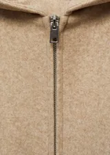 Chaqueta beige con capucha, cierre frontal con cremallera, puños y cintura elásticos.