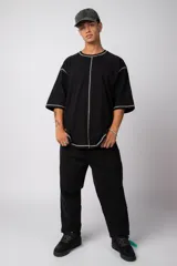 Remera negra oversize con mangas cortas y costuras a la vista en color blanco.