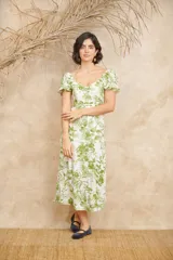 Vestido midi blanco con estampado floral en tonos verdes, escote en V, mangas cortas abullonadas y corte evasé con abertura lateral.