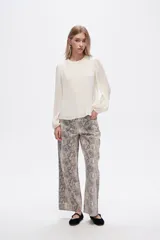 Pantalón jean ancho con estampado de piel de serpiente en tonos beige y gris.