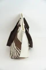 Bolso tipo tote con estampado de estrellas negras sobre fondo beige y una franja horizontal negra con glitter.