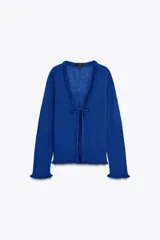 Chaqueta azul de punto con manga larga, volantes en el escote y en los puños, y cierre frontal con lazada.