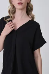 Blusa holgada de poliéster color blanco, con escote en V profundo y pinzas frontales que generan caída. Mangas cortas.