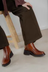 Bota corta color marrón con textura símil cuero de cocodrilo, caña baja, punta redondeada y taco cuadrado.