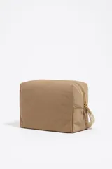 Neceser grande Bimba y Lola color beige, de nylon con estructura blanda y cierre de cremallera. Tiene un bolsillo interior, tirador de piel y logo metálico.