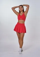 Conjunto deportivo rojo compuesto por un top con tirantes finos cruzados en la espalda y una minifalda tableada.