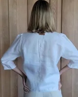 Camisa color beige claro con cuello con volados y mangas 3/4 abullonadas.