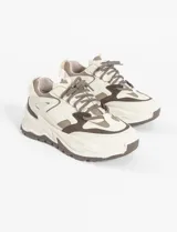 Zapatillas urbanas blancas con detalles en negro, cordones negros y suela chunky.
