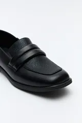 Mocasín negro de cuero sintético con punta cuadrada y detalle de bordado a tono en la capellada. Taco de 2,5cm.