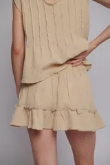 Minifalda color beige de muselina de algodón con cintura elastizada y volado en el ruedo.