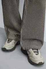 Zapatillas deportivas color crema con cordones, suela gruesa con diseño irregular y detalles en gris.