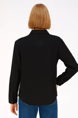 Camisa negra de poliéster con solapa, cierre con botones y mangas largas.