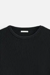 Sweater negro de punto con estructura de canalé, corte relaxed fit, cuello redondo y cierre de botones en el hombro.
